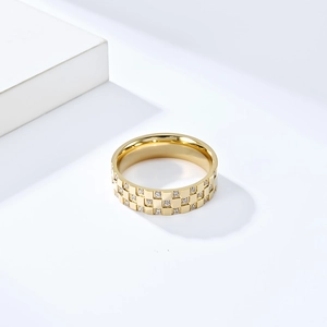 Détail macro d'une bague dorée à damier avec des pierres de zircone incrustées