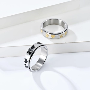 Close-up of spinning stainless steel rings featuring paw prints and heart engravings