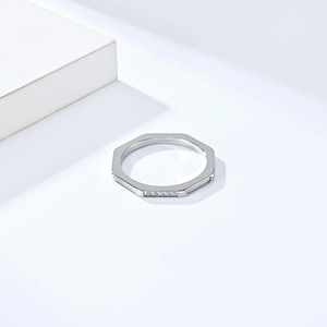 Détail macro d'une bague argentée octogonale ornée de cinq zircons sur surface lisse