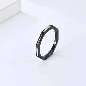 Détail macro d'une bague hexagonale en acier noir avec incrustation de nacre et zircons