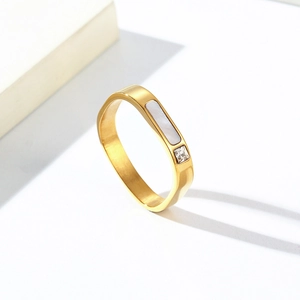 Détail d'une bague dorée en acier avec incrustation de nacre blanche et pierre de zircon