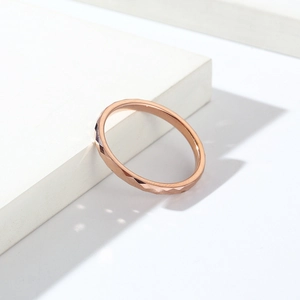 Makroaufnahme eines roségoldenen Wolframrings mit facettiertem Rautenmuster und Politur