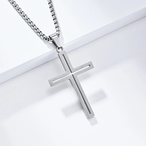 Détail macro du pendentif croix en acier titane argenté sur une chaîne à mailles carrées
