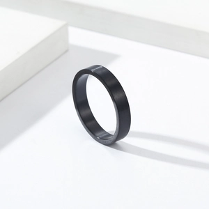 Gros plan d'une bague de 4mm en acier titane noir mat sur une plateforme blanche