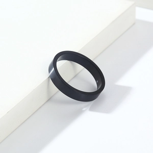 Détail d'une bague en acier titane noir mat de 4 mm sur un support blanc minimaliste