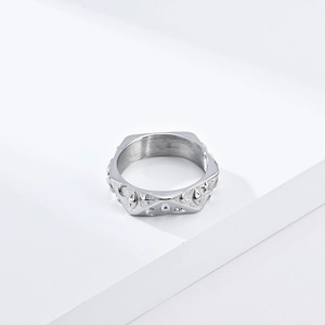 Detalle de anillo plateado con grabados de luna, estrella y ojo en soporte geométrico
