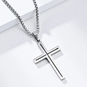 Détail du pendentif croix en titane brossé avec chaîne maille box sur socle blanc