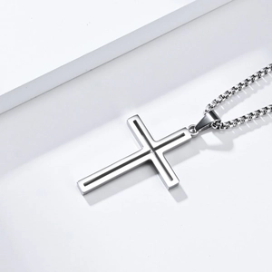 Gros plan détaillé d'un pendentif croix géométrique ajouré avec une chaîne maille box