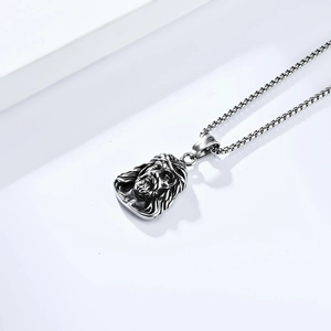 Macro detail of a vintage Jesus head pendant made of titanium steel with box chain