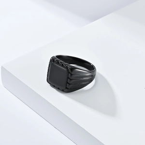 Macro detail of a black square signet ring with textured groove patterns on the band