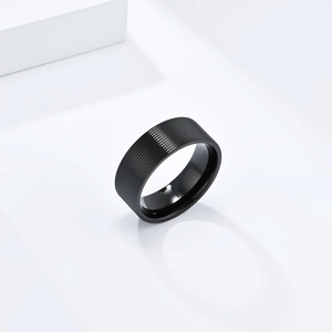 Close-up of matte black titanium ring with horizontal grooved texture on white steps