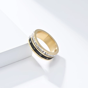 Gros plan d'une bague dorée avec chiffres romains, émail noir et cristaux pavés