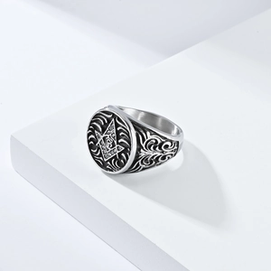 Vintage stainless steel Freemason ring with G symbol and floral relief on white stand