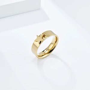 Detail of gold stainless steel ring with flat band and star pendant on white podium