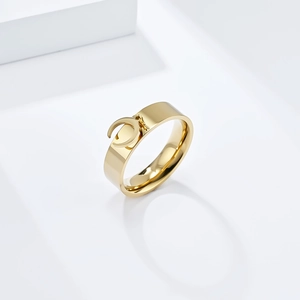 Detailed view of a gold-colored moon pendant on a minimalist wide-band titanium steel ring