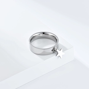 Detail of silver stainless steel ring featuring a dangling star charm on a white stand
