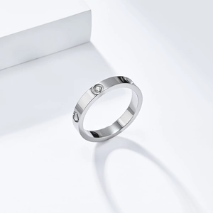 Macro shot of silver titanium steel ring with heart patterns and round zircons inlay