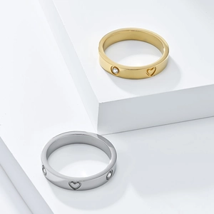Detail of 18K gold and silver heart rings with cubic zirconia on white geometric stand