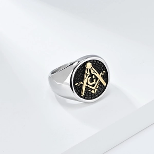 Detailed close-up of a silver Masonic ring with a gold G logo on a black textured surface