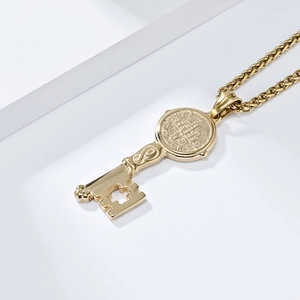 Close-up of gold St. Benedict key pendant with cross cutout on white background