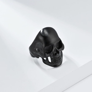 Matte black stainless steel skull ring with punk gothic details on a white background