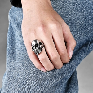 Men's punk skull ring in matte silver stainless steel shown on hand over denim