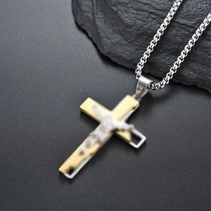 Detail shot of a two-tone silver and gold crucifix pendant on a box chain for men