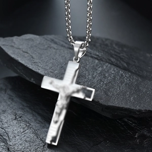 Polished stainless steel cross necklace with Jesus crucifix on black stone background