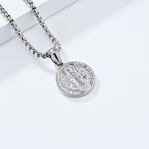 Macro shot of silver St. Benedict medal pendant with box chain on white steps