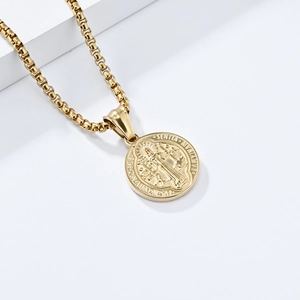 Close-up of gold Saint Benedict medal pendant with detailed engraving on box chain