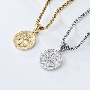 Saint Benedict medal necklaces in gold and silver steel on a minimalist white display