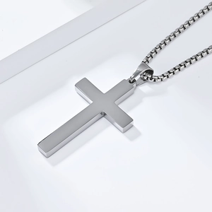 Macro shot of minimalist stainless steel cross pendant with brushed metal texture and box chain