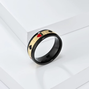 Gros plan de la bague rotative en titane noir avec motifs de poker coeur et trèfle dorés