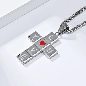 Détail du pendentif croix avec lettres I LOVE YOU et cœur rouge sur chaîne argentée