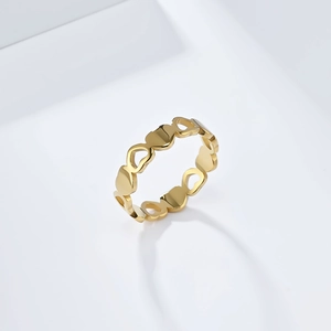 Macro detail of gold-plated stainless steel ring with alternating hollow heart patterns