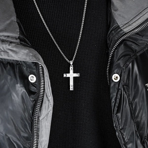 Pendentif crucifix en acier inoxydable argenté pour homme sur un pull noir chic