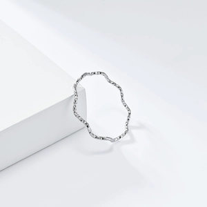 Minimalist 1mm silver wavy stainless steel ring with hammered texture on white geometric stand