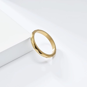 Detailed view of a golden geometric rhombus ring resting on a minimalist white block