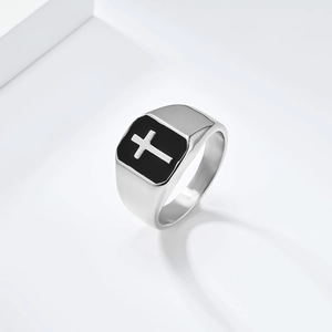 Detail of silver stainless steel signet ring with black enamel cross on a white background