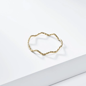 Minimalist 1mm gold wave ring with hammered texture displayed on a white platform