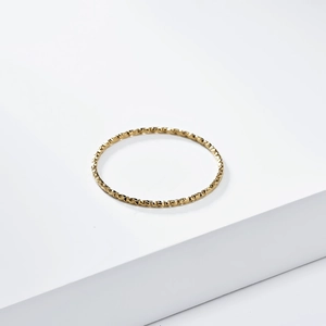 Detail of 18K gold plated titanium ring with fine diamond-cut textured surface finish
