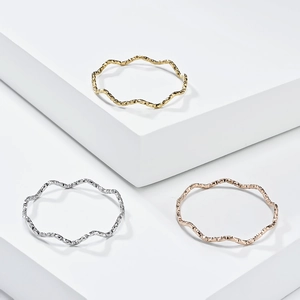 Three-piece set of wave-textured rings in gold, silver, and rose gold on geometric blocks