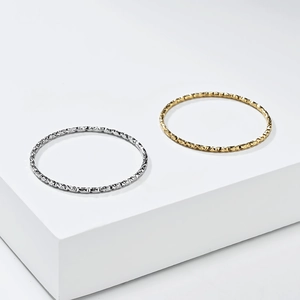 Detail of 1mm titanium steel rings featuring geometric textures in gold and silver