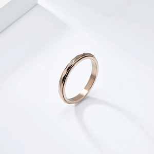Detail of rose gold spinner ring featuring geometric diamond-cut surfaces on white stand