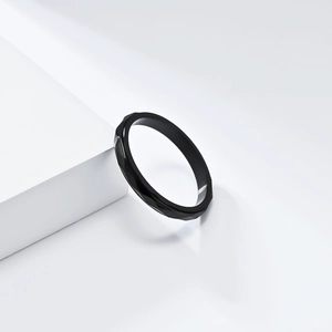 Detail of a rotating black stainless steel ring featuring a faceted geometric surface