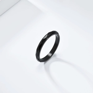 Macro shot of minimalist black stainless steel ring with geometric diamond-cut surfaces