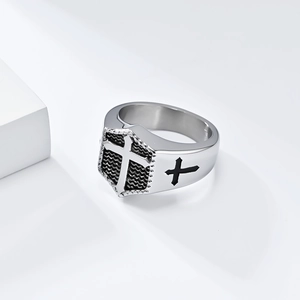 Detailed view of silver cross signet ring with black embossed shield and punk textures