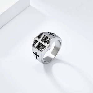 Detail of vintage stainless steel signet ring with embossed cross and textured black background