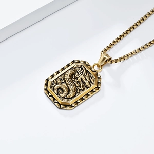Detail van een gouden draak reliëf hanger aan een robuuste roestvrijstalen box ketting