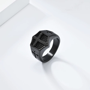 Detail of gothic black titanium cross signet ring with textured patterns on white pedestal